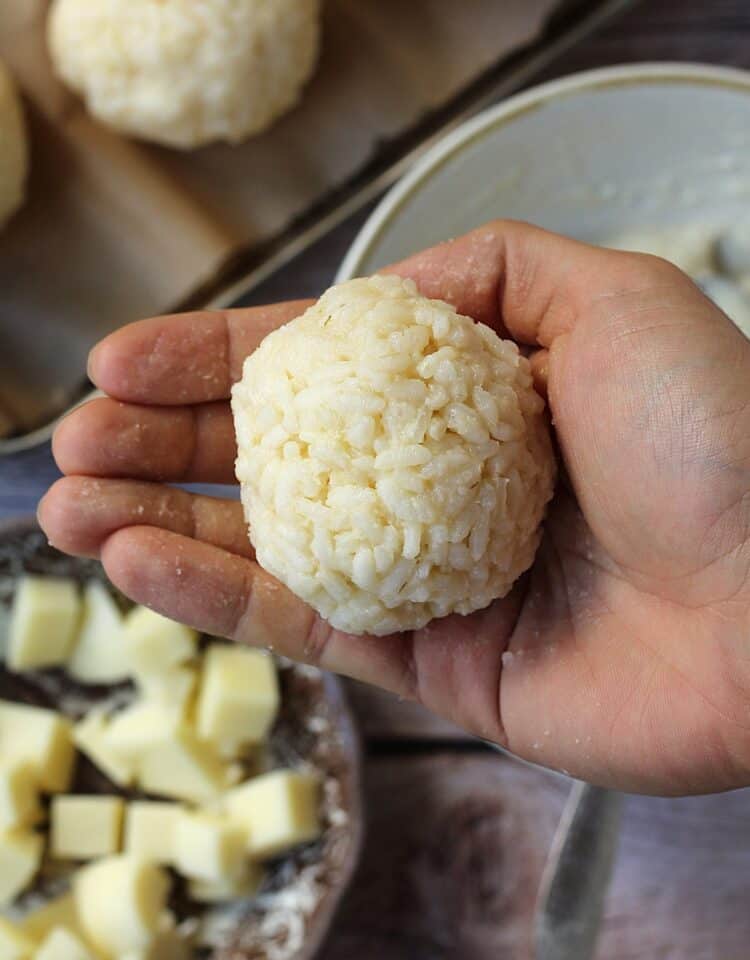 Arancini ball of rice in palm of hand.