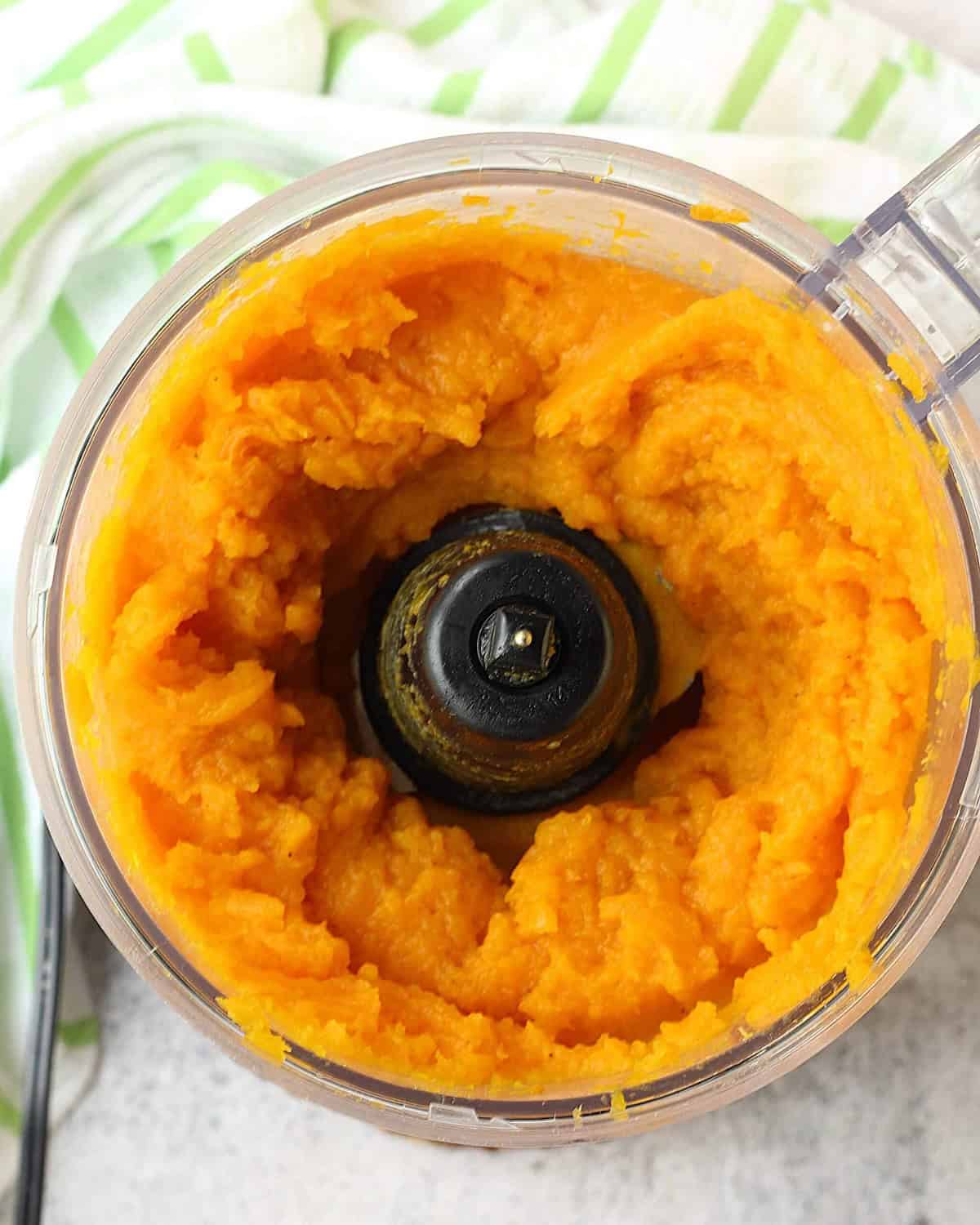 Puréed butternut squash in bowl of food processor.