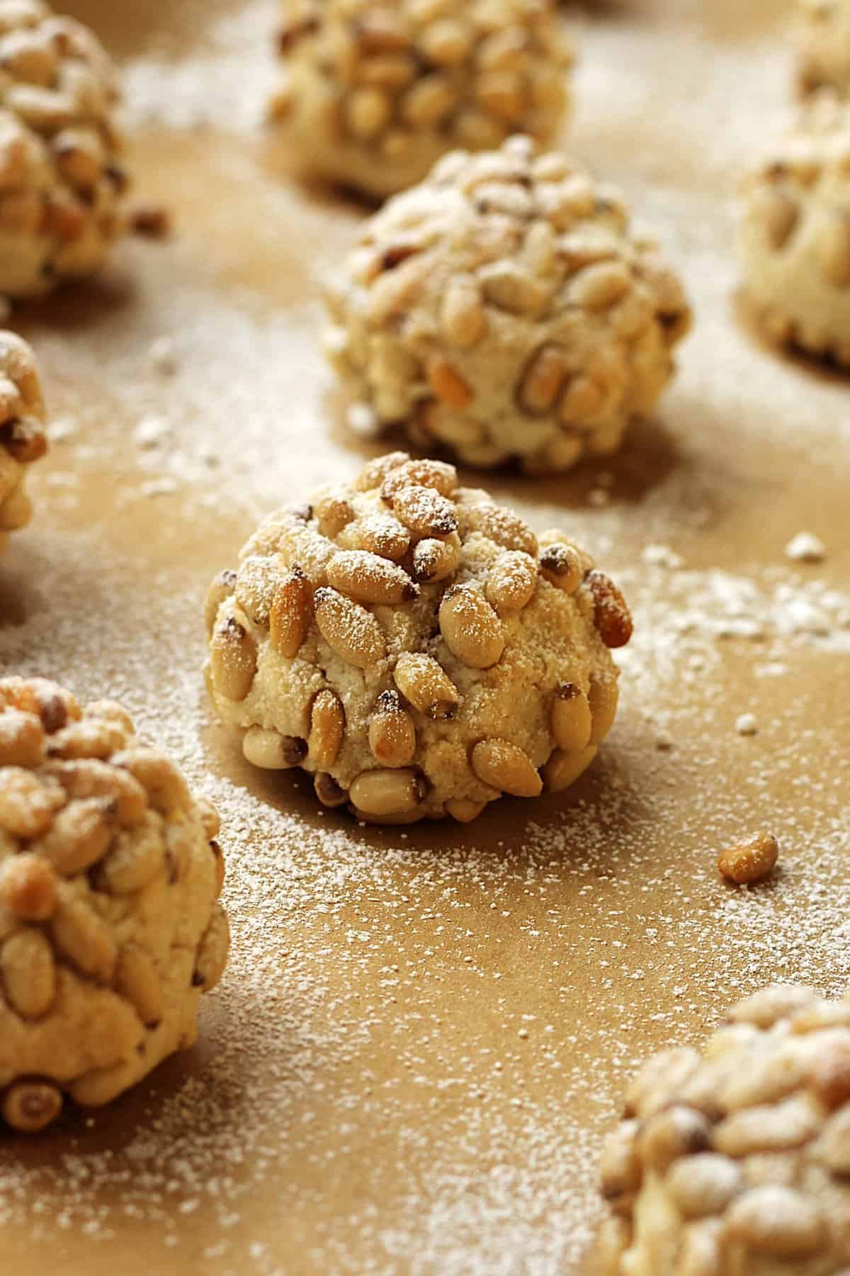 Pine nut cookies (pignoli) on baking sheet dusted with powdered sugar.