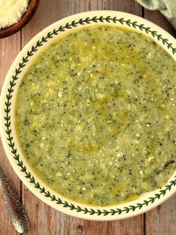 Bowl with polenta and broccoli (frascatula) with spoon on side.