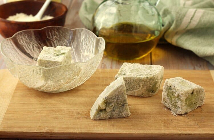 Floured cubes of frascatula on wood board.
