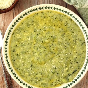 Sicilian polenta with broccoli (frascatula) in bowl with spoon and bowl of cheese on the side.