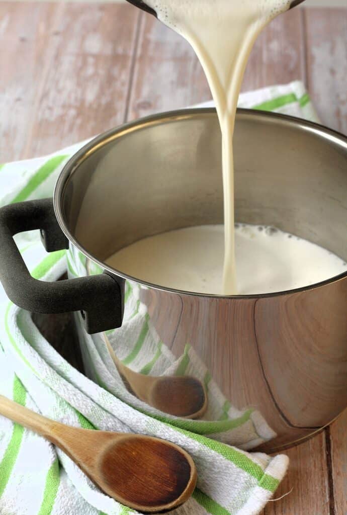 Almond milk poured into sauce pan for making vegan ricotta.
