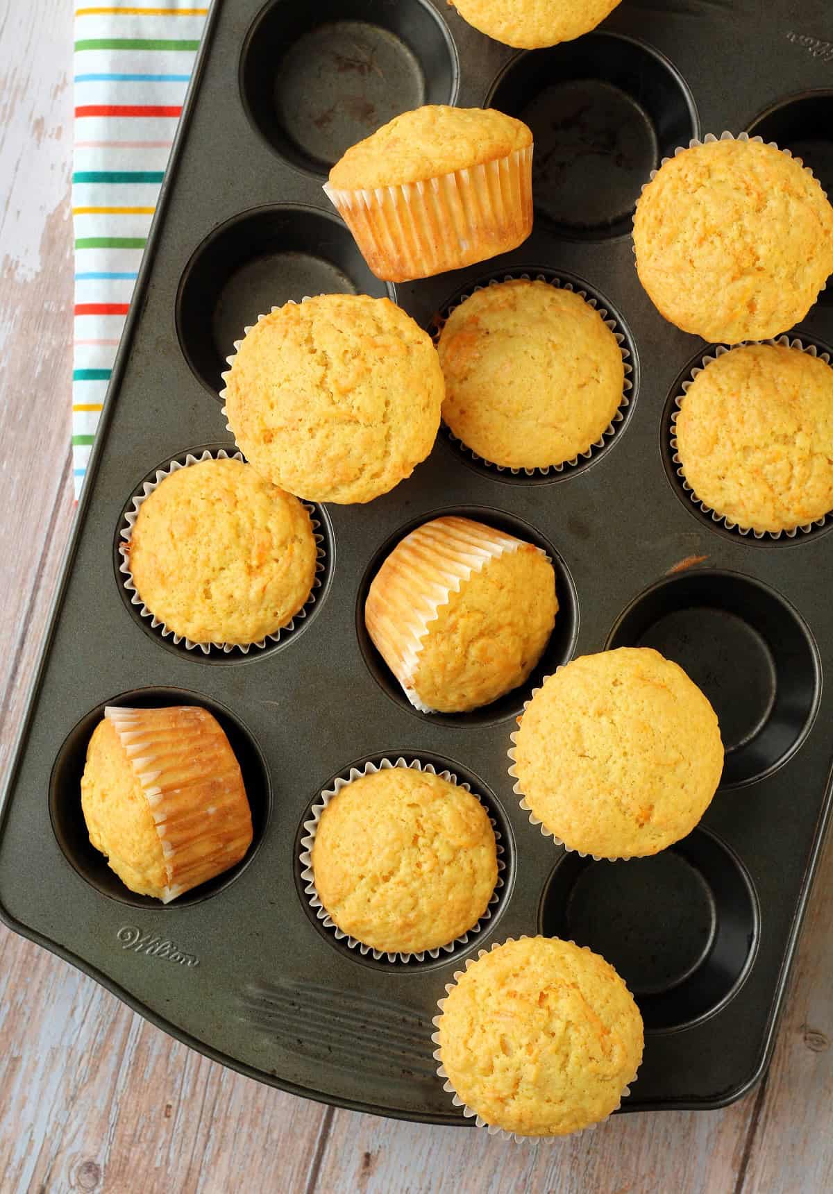 Carrot cupcakes on muffin tin, some lifted out and resting on rim of pan.