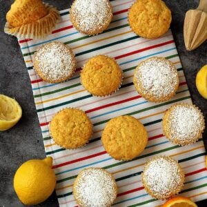 Citrus and carrot cupcakes on colorful dish cloth with orange and lemon wedges around them.