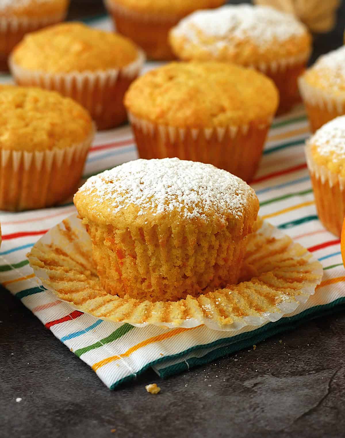 Italian orange, lemon and carrot cupcake on dish cloth with wrapper peeled.