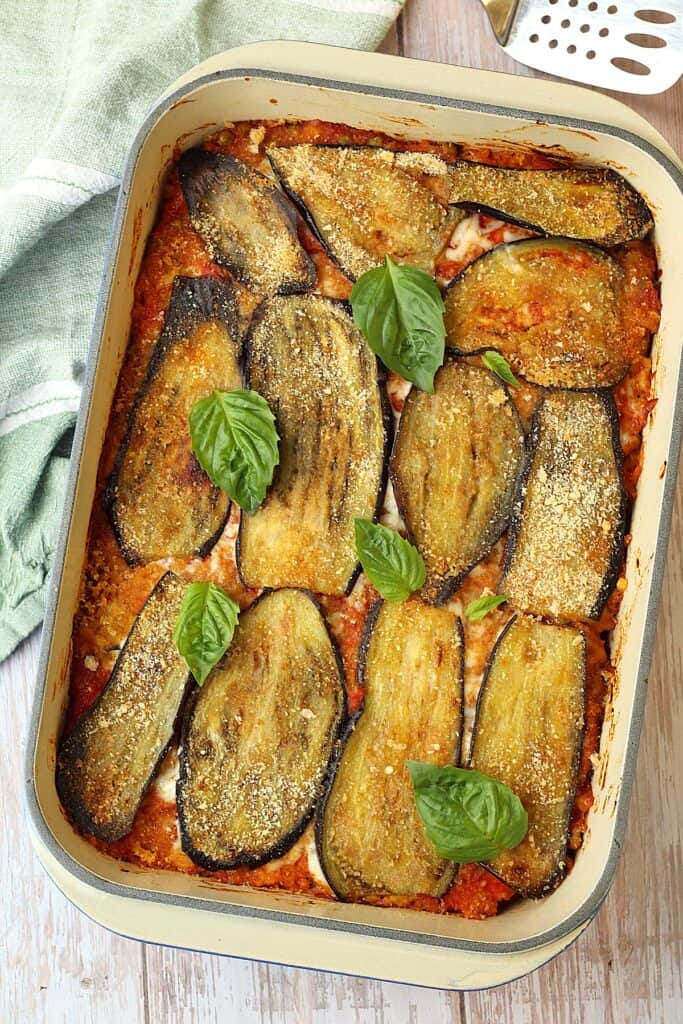 Baked rice and eggplant timbale topped with basil leaves in rectangular casserole.