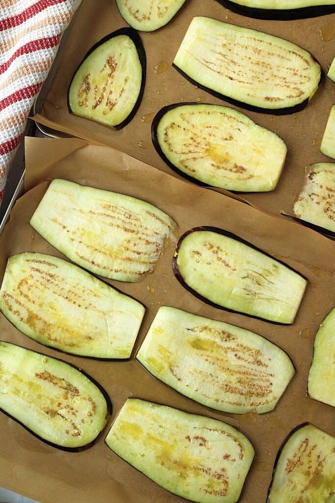 Sliced eggplant on greased baking sheets.