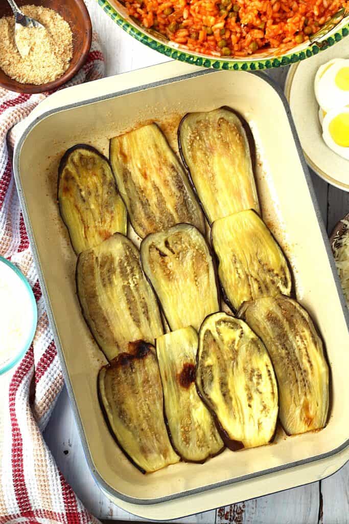 Layered eggplant slices on bottom of casserole dish.