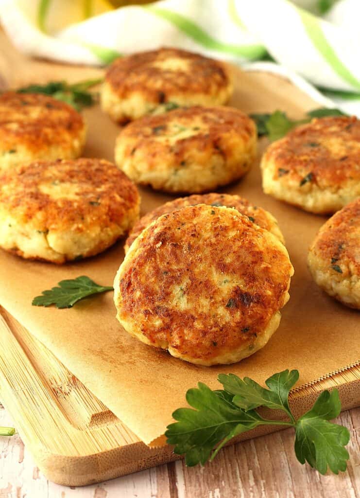 Sicilian cauliflower meatballs on wood board with parsley leaves.