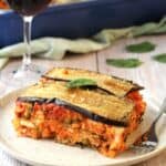 Sicilian rice and eggplant timbale casserole on plate with wine glass behind it.