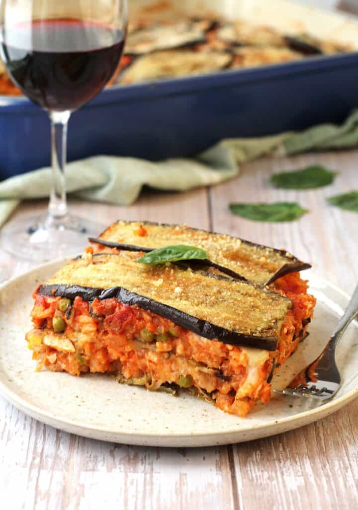Sicilian rice and eggplant timbale casserole on plate with wine glass behind it.