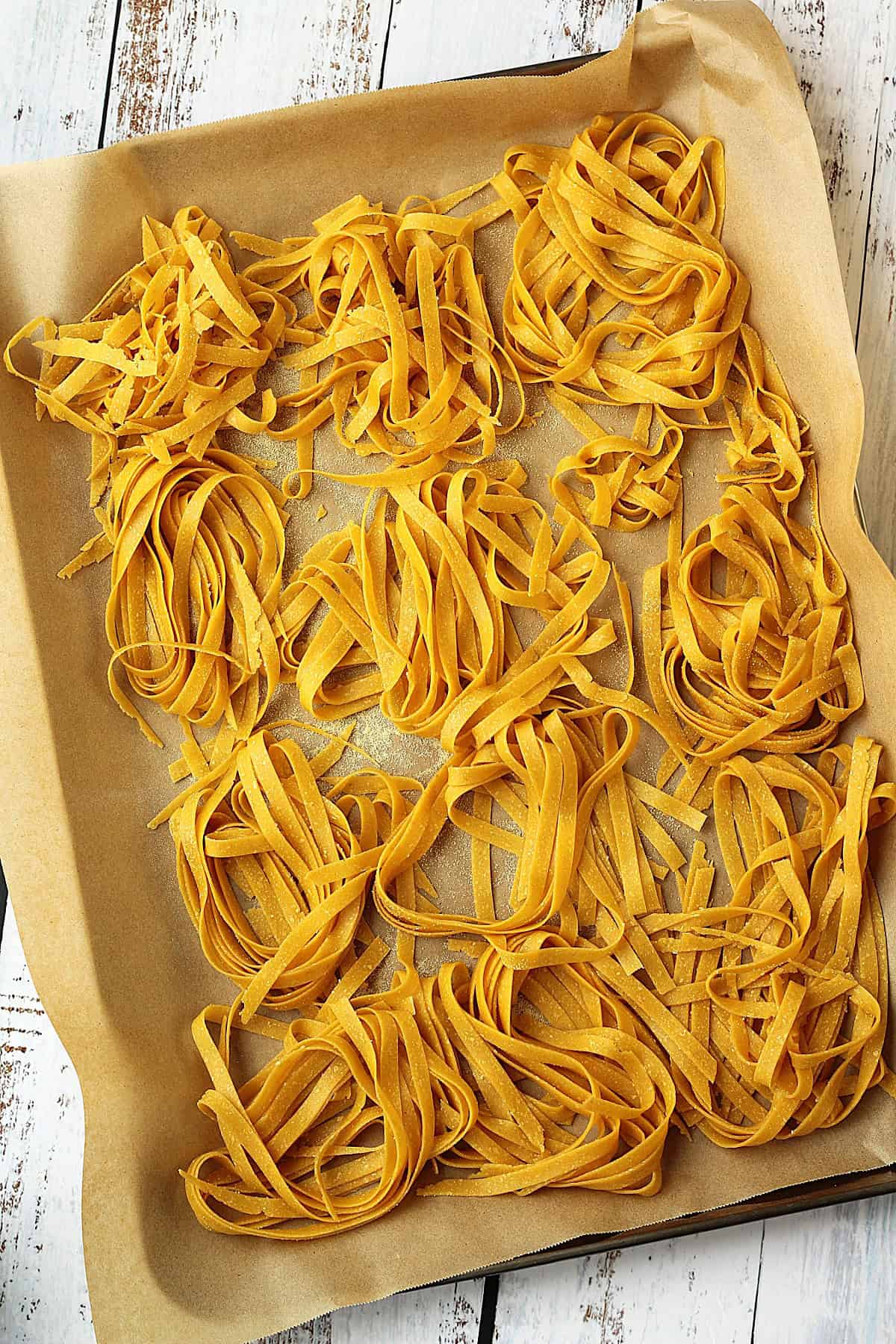 Nests of fresh chickpea flour pasta on baking sheet.