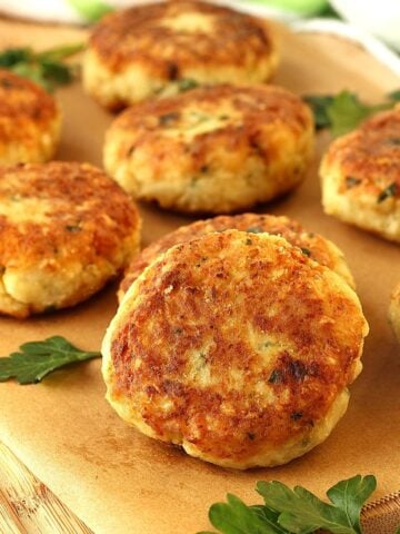Sicilian cauliflower meatballs on wood board with parsley leaves.