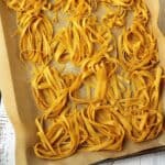Homemade chickpea flour tagliatelle nests on baking sheet.