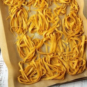 Homemade chickpea flour tagliatelle nests on baking sheet.