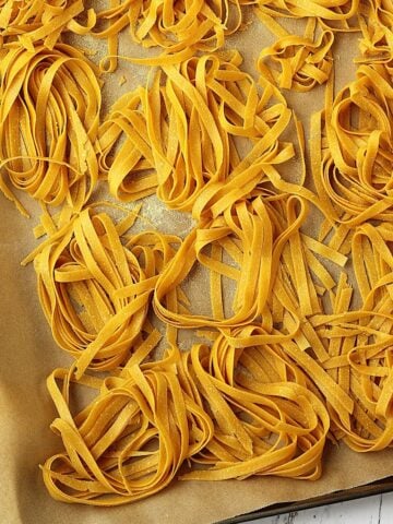 Homemade chickpea flour tagliatelle nests on baking sheet.
