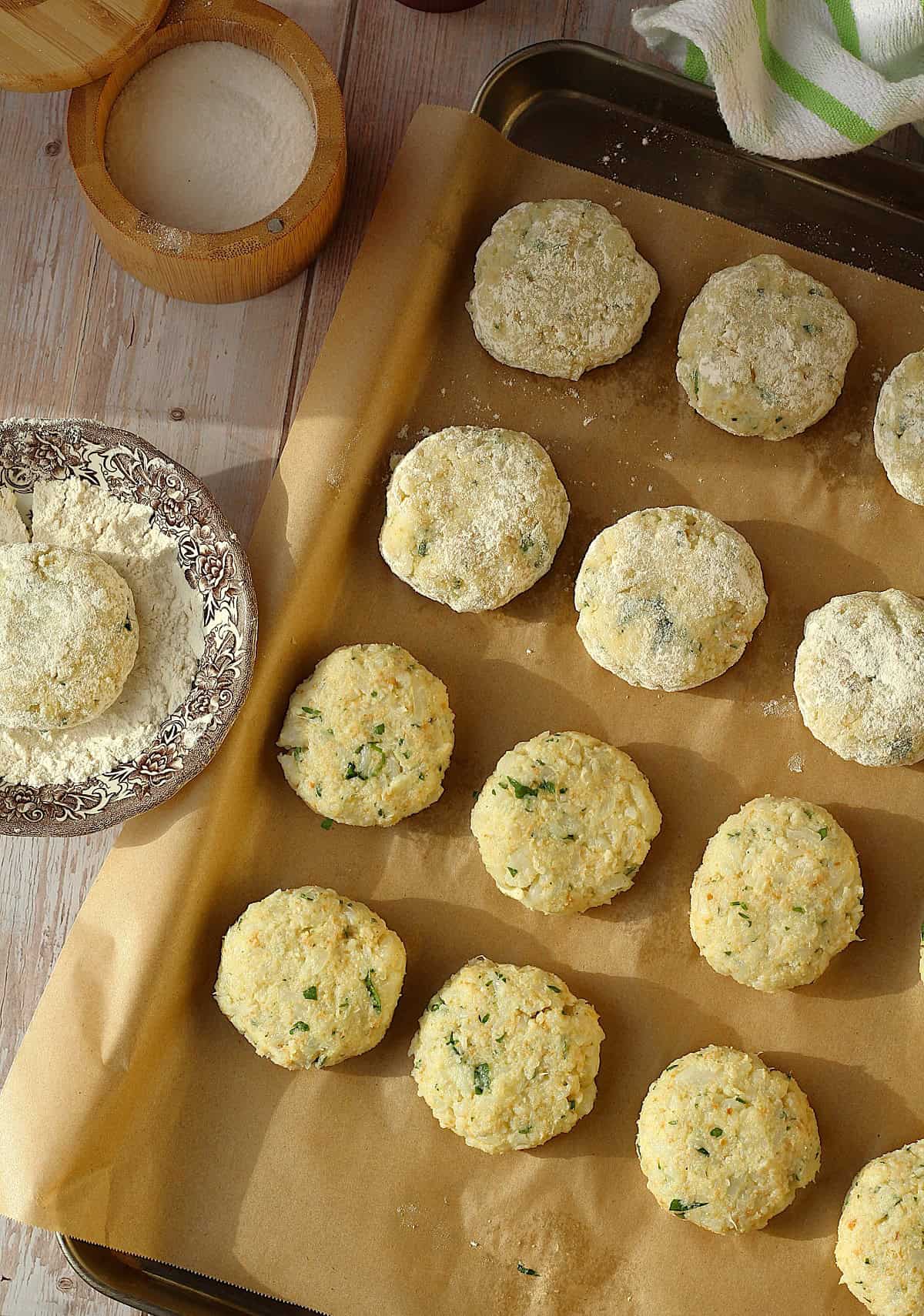 Shaped cauliflower meatballs dredged in flour on baking sheet.