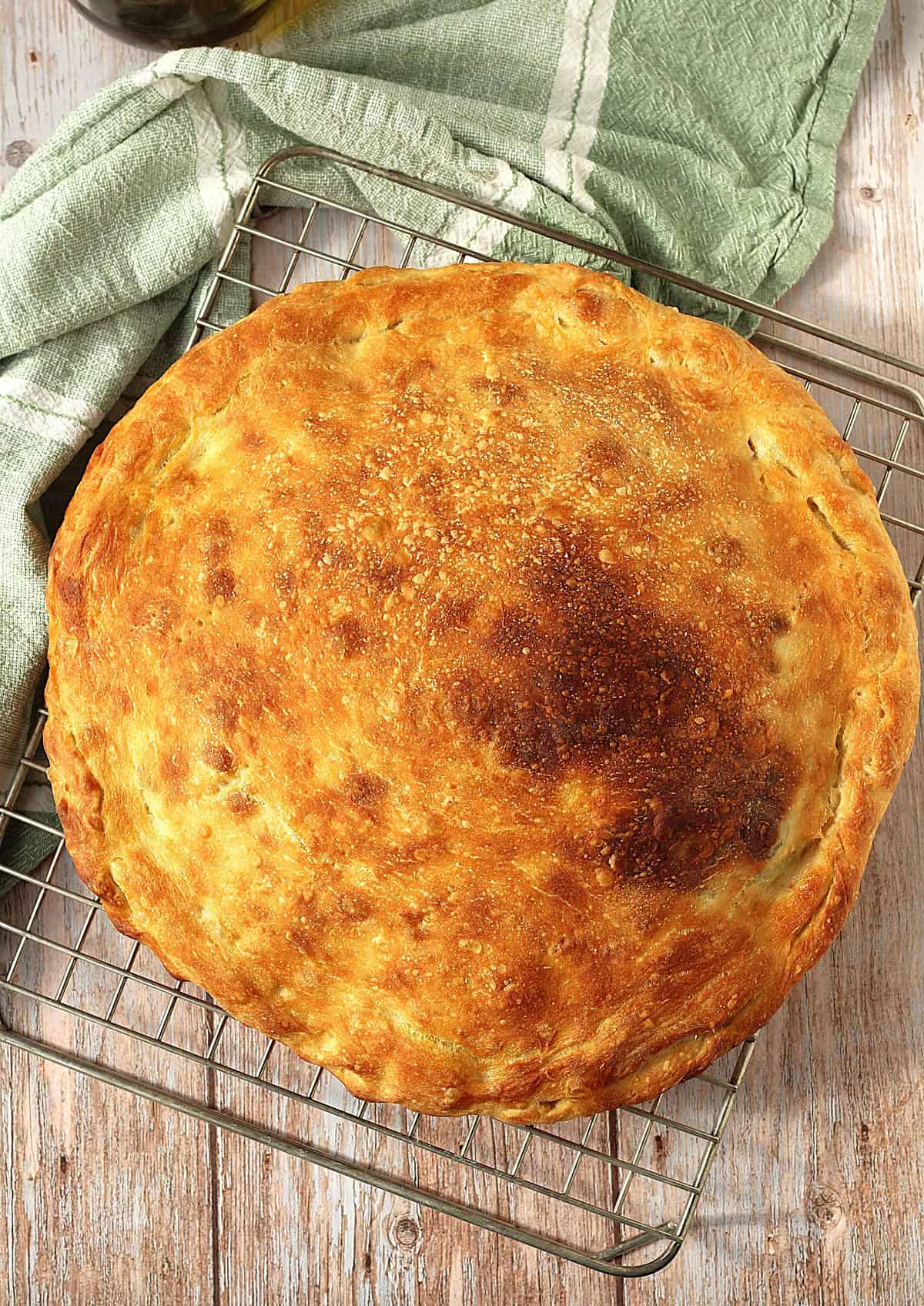Whole baked scacciata bread on wire rack.