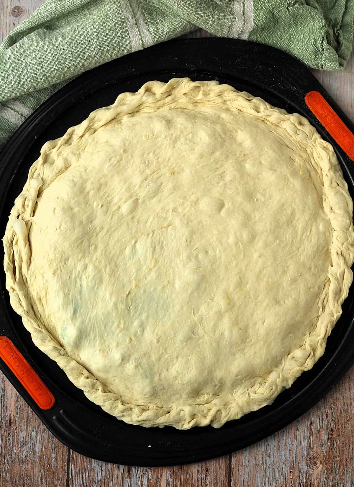 Assembled double crust scacciata bread on pizza pan.