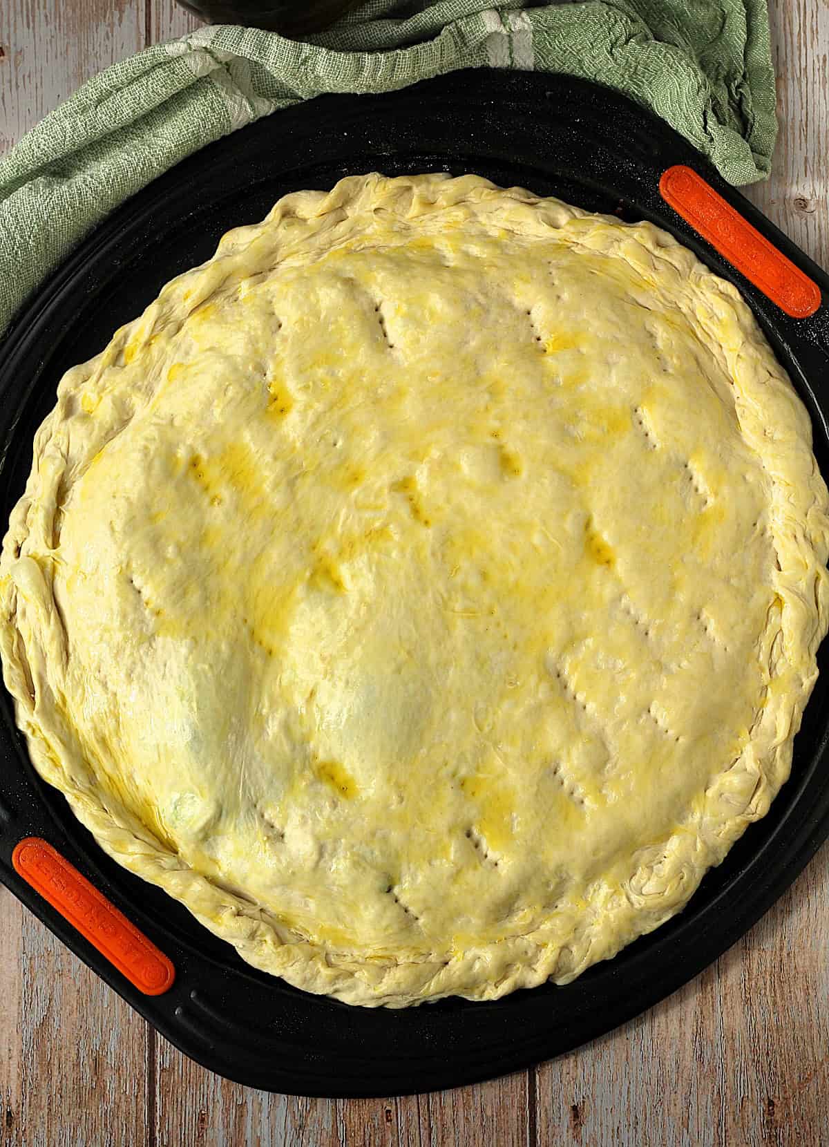 Scacciata dough brushed with olive oil on pizza pan.