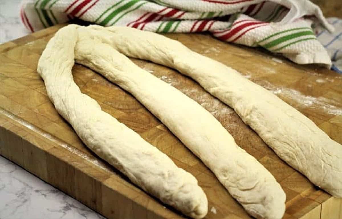 Bread dough divided into 3 long ropes for making braided bread.
