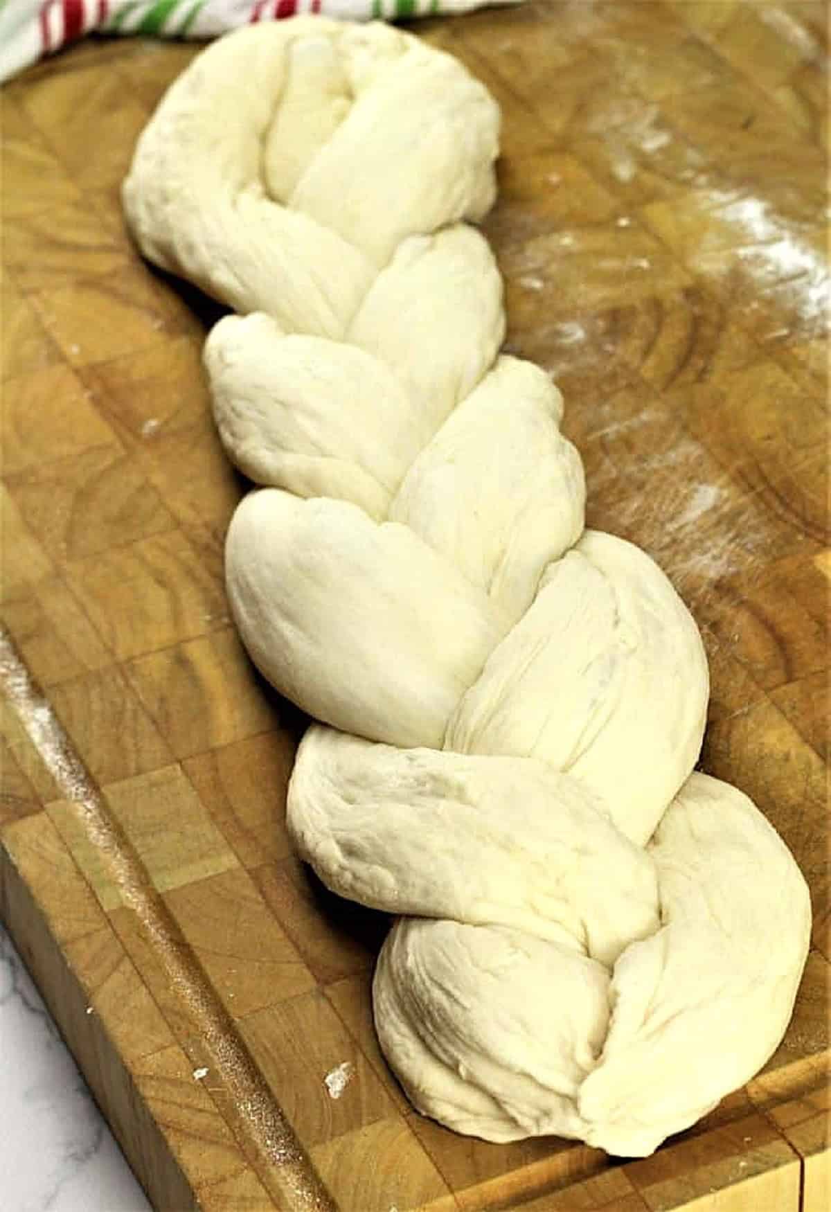 Braided bread dough on wood board.