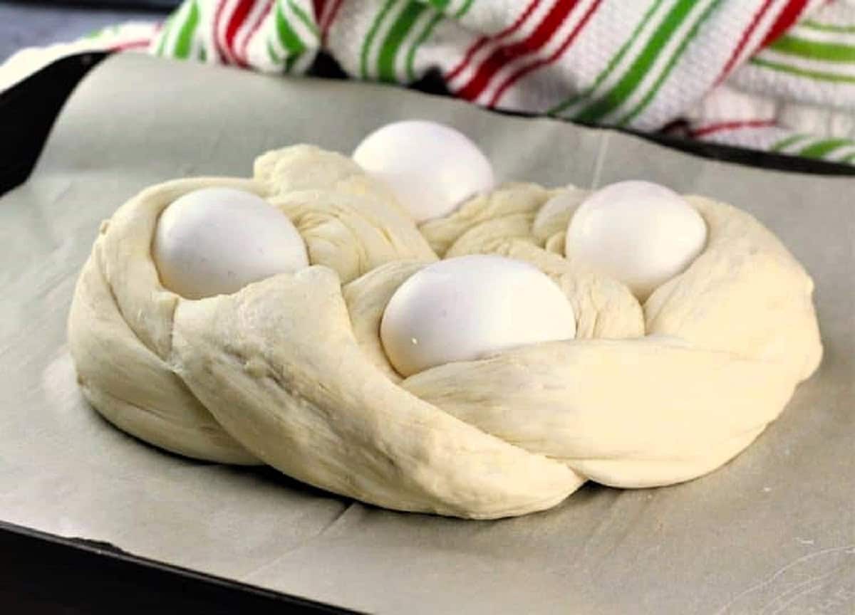 Braided Easter bread with eggs on baking sheet.