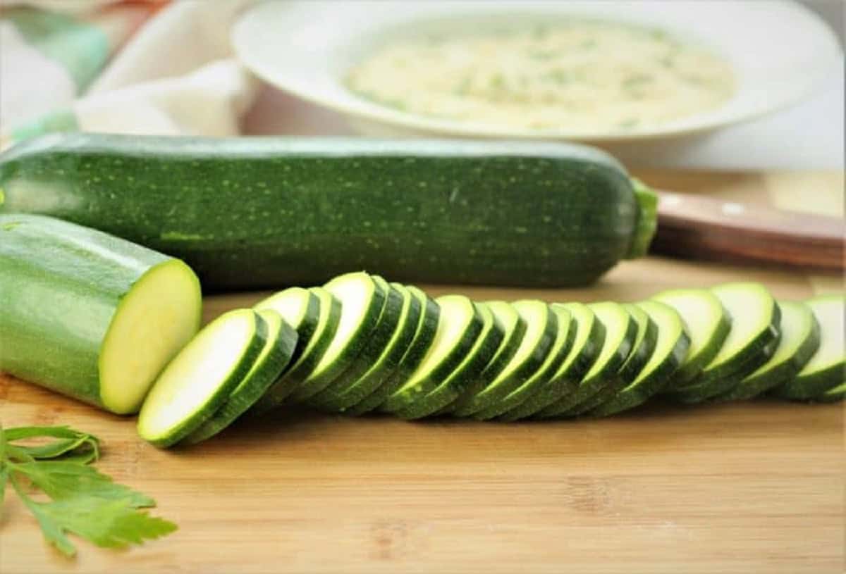 Sliced zucchini into rounds on wood board.