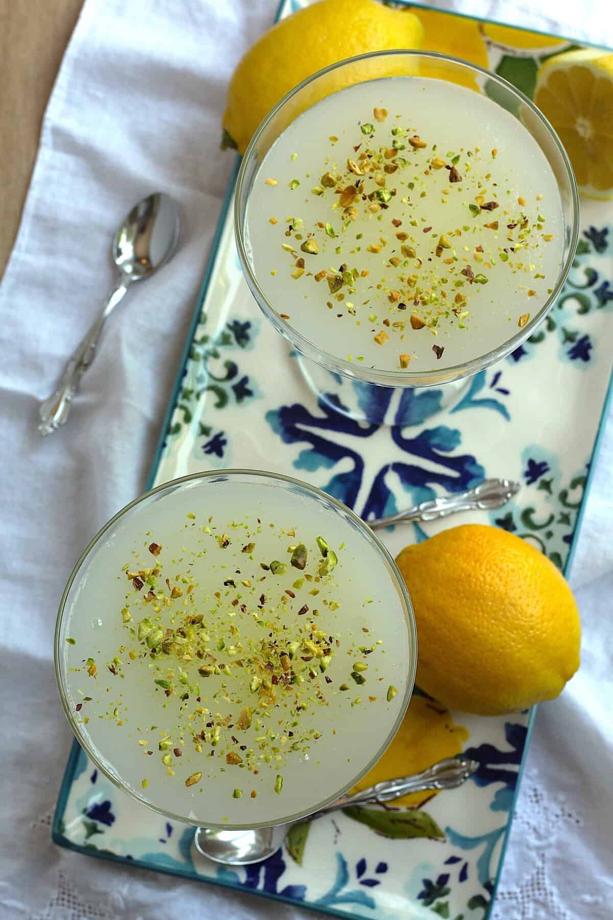 Sicilian gelo di limone in glasses on plate next to lemons.