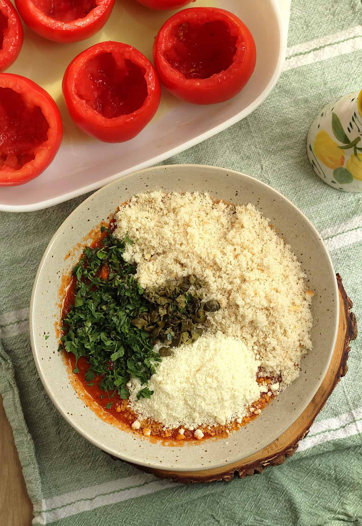 Tomato pulp in bowl with breadcrumbs, grated cheese, parsley, basil and capers for stuffed tomatoes.