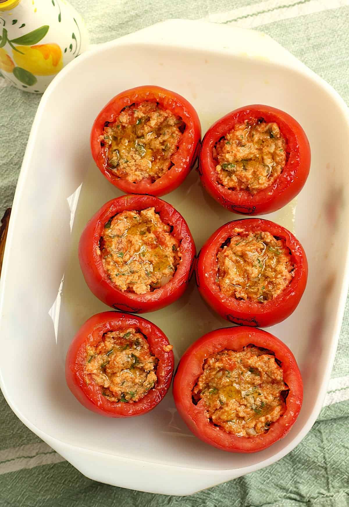 Stuffed tomatoes with breadcrumb filling in casserole dish ready to be baked.
