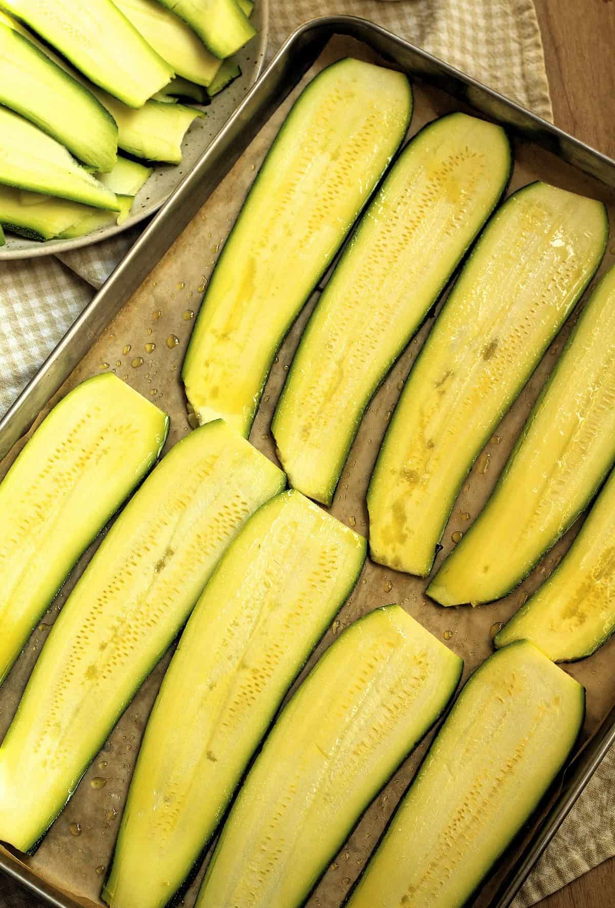 Sliced zucchini on baking sheet for zucchini parmigiana.
