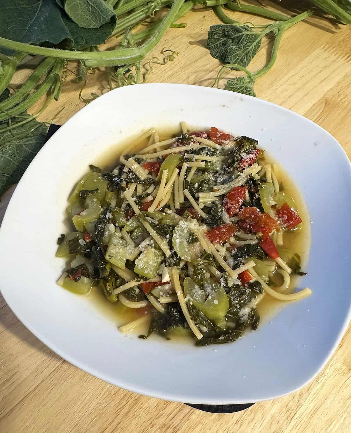 Sicilian tenerumi with pasta in bowl topped with grated cheese.
