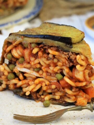 Slice of anelletti al forno with eggplant on plate with fork.