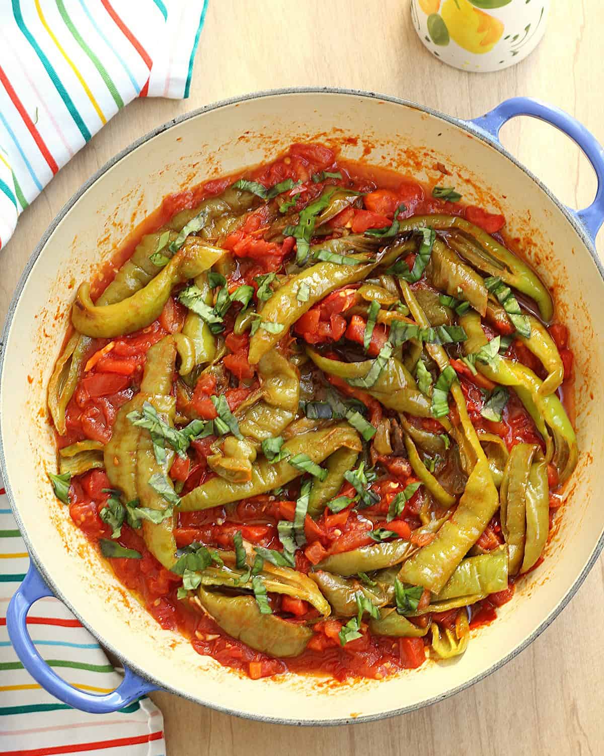 Italian long sweet peppers with tomatoes in large blue skillet.