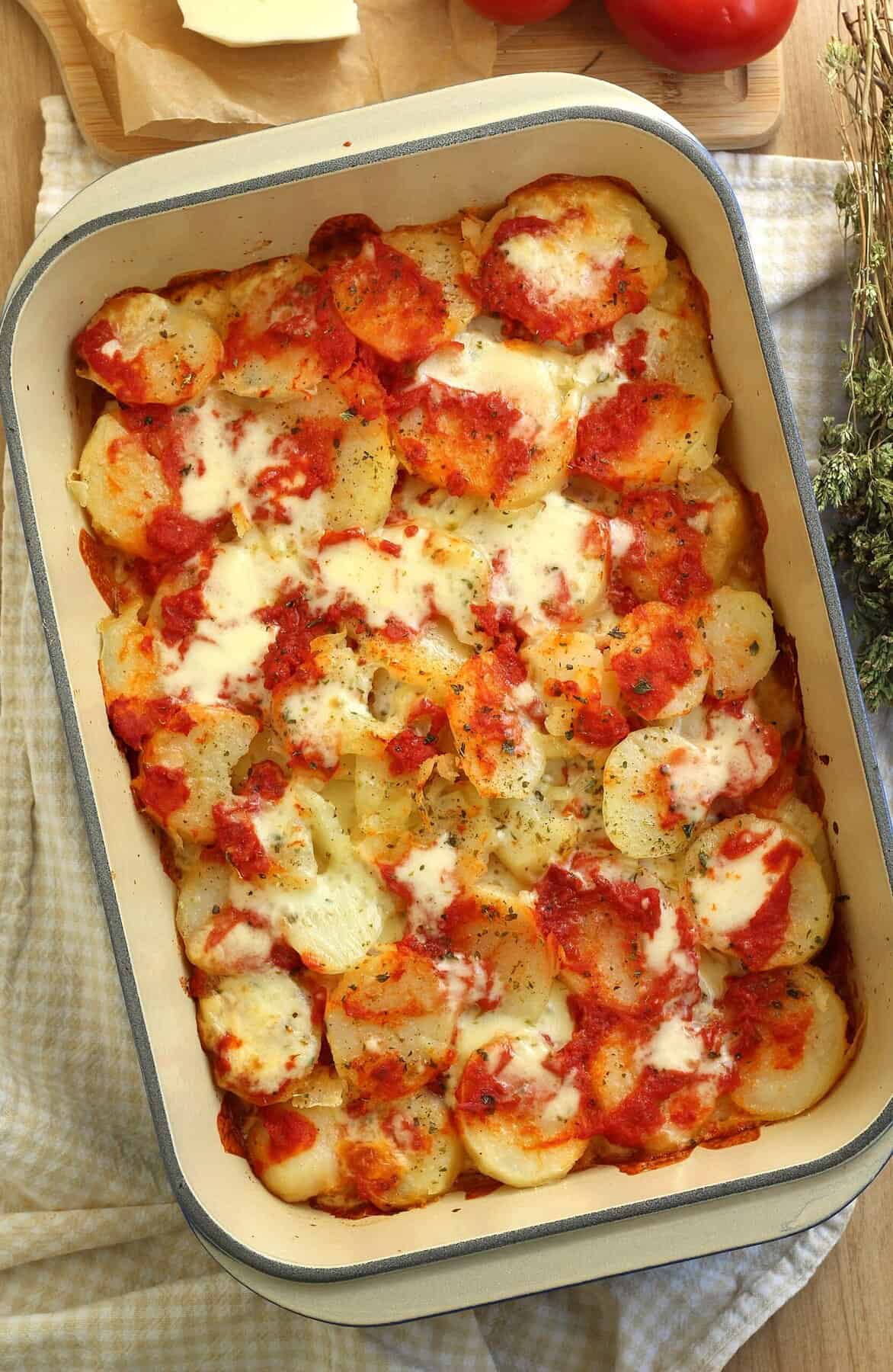 Roasted potatoes alla pizzaiola in casserole dish.