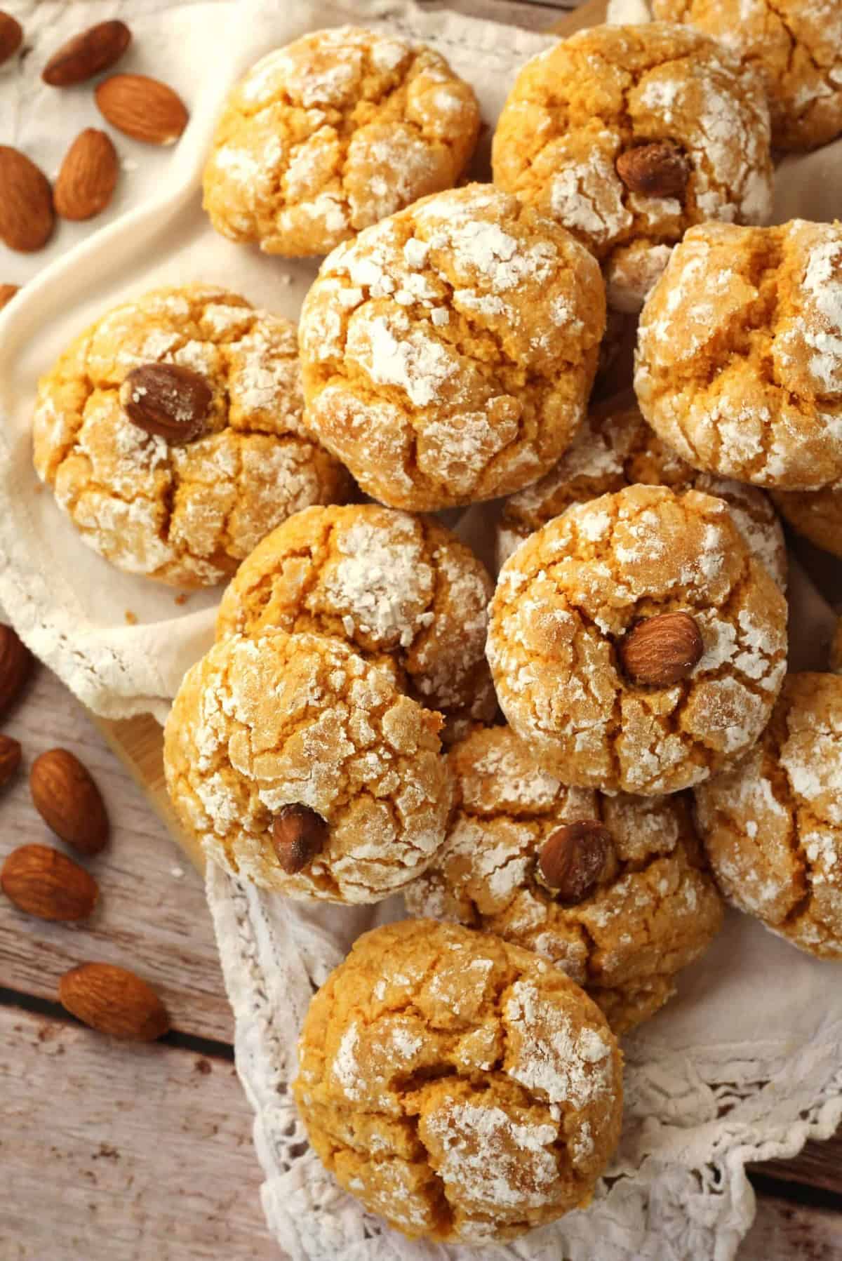 Soft pumpkin cookies with almond flour topped with almonds piled on plate.