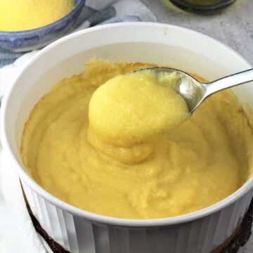 Creamy oven baked polenta is casserole dish spooned.