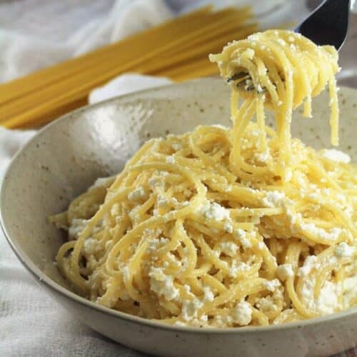 Pasta with ricotta in bowl twirled with fork.