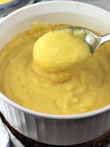 Creamy oven baked polenta spooned in white casserole dish.