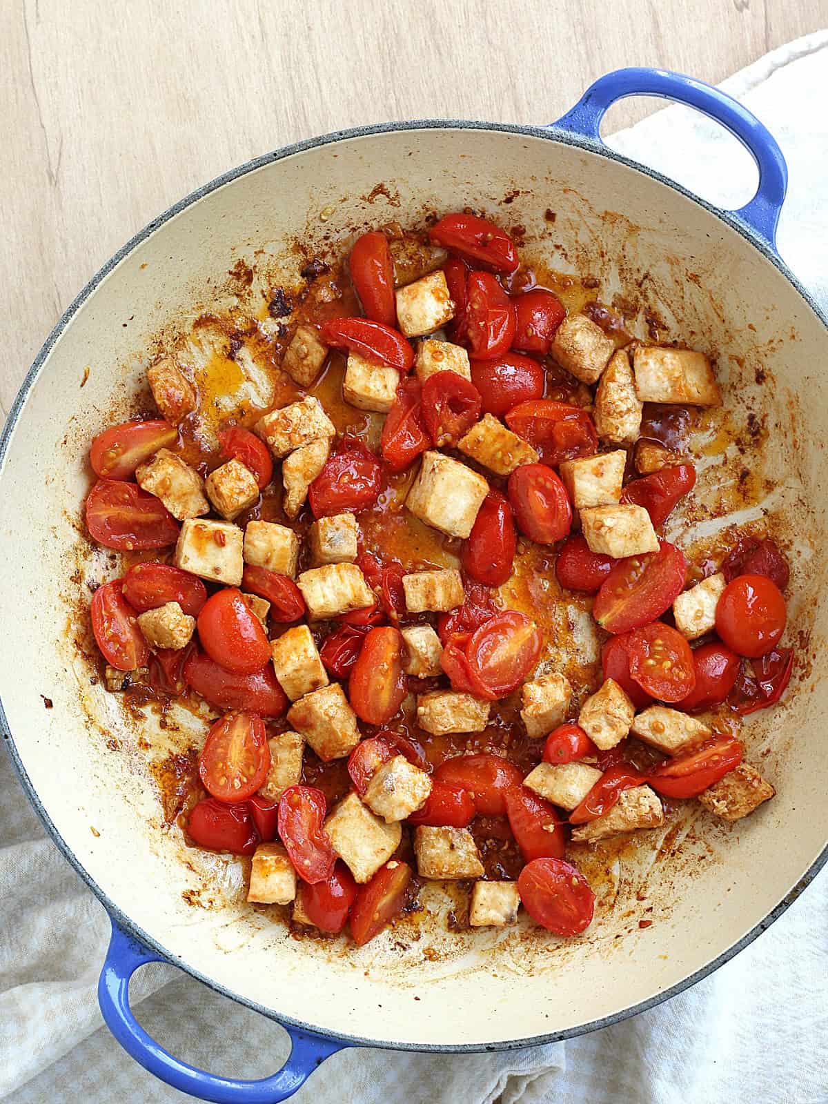 Cubed swordfish and halved cherry tomatoes in skillet for pasta with swordfish recipe.