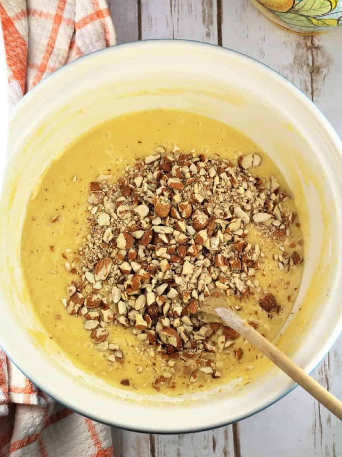 Chopped almonds added to sheet pan biscotti batter in large bowl.
