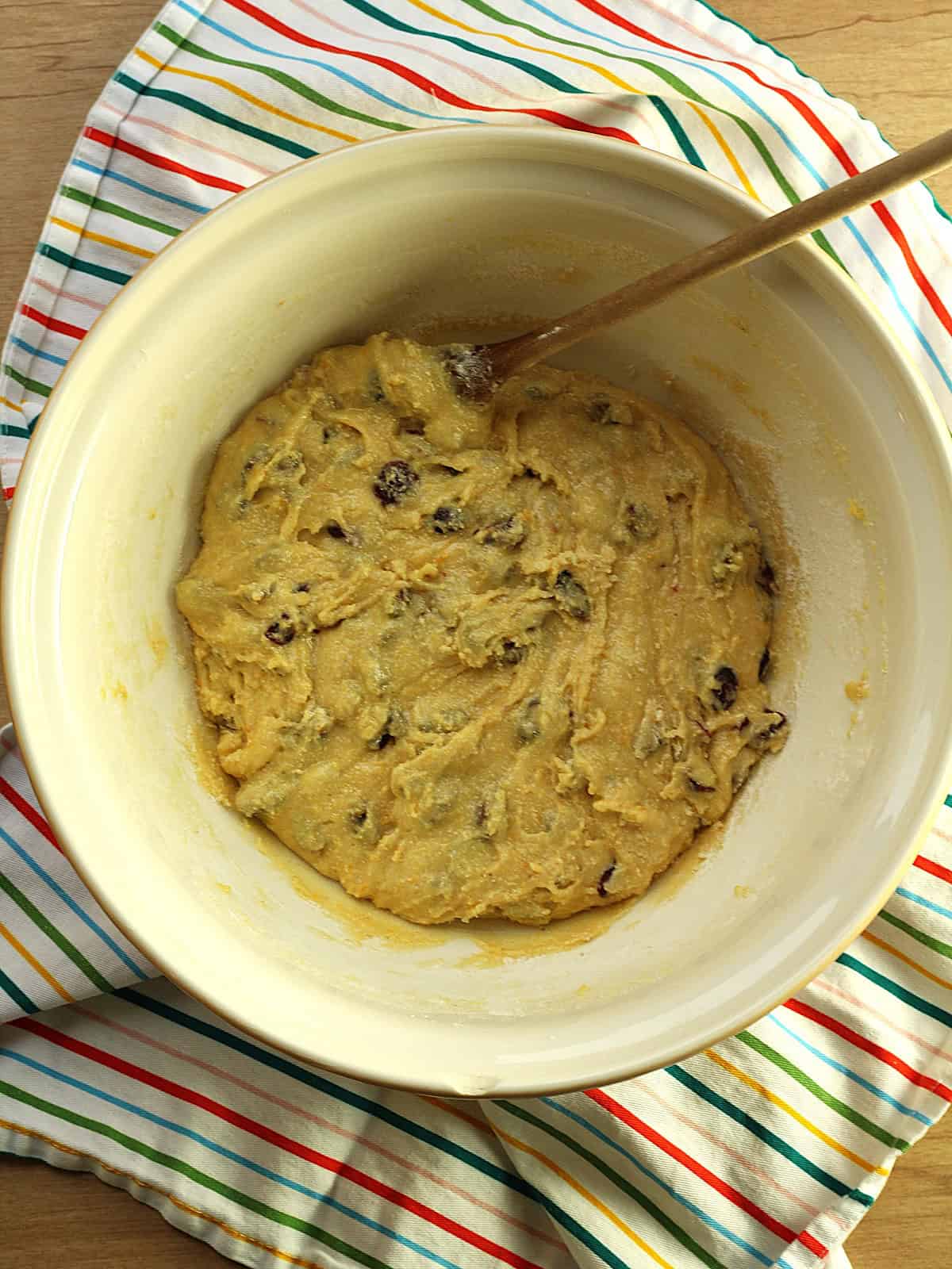 Cranberry pistachio cornmeal biscotti batter in bowl with wooden spoon.