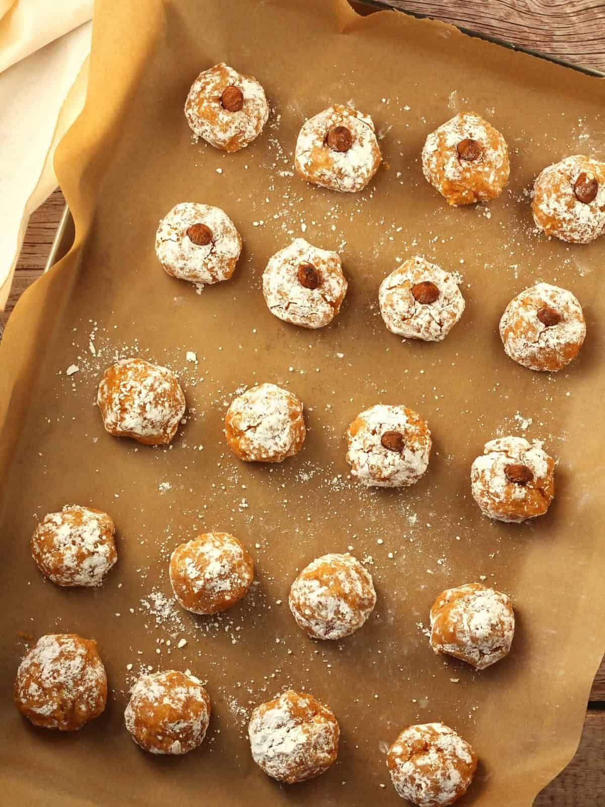 Soft pumpkin almond flour cookies topped with almonds on baking sheet.