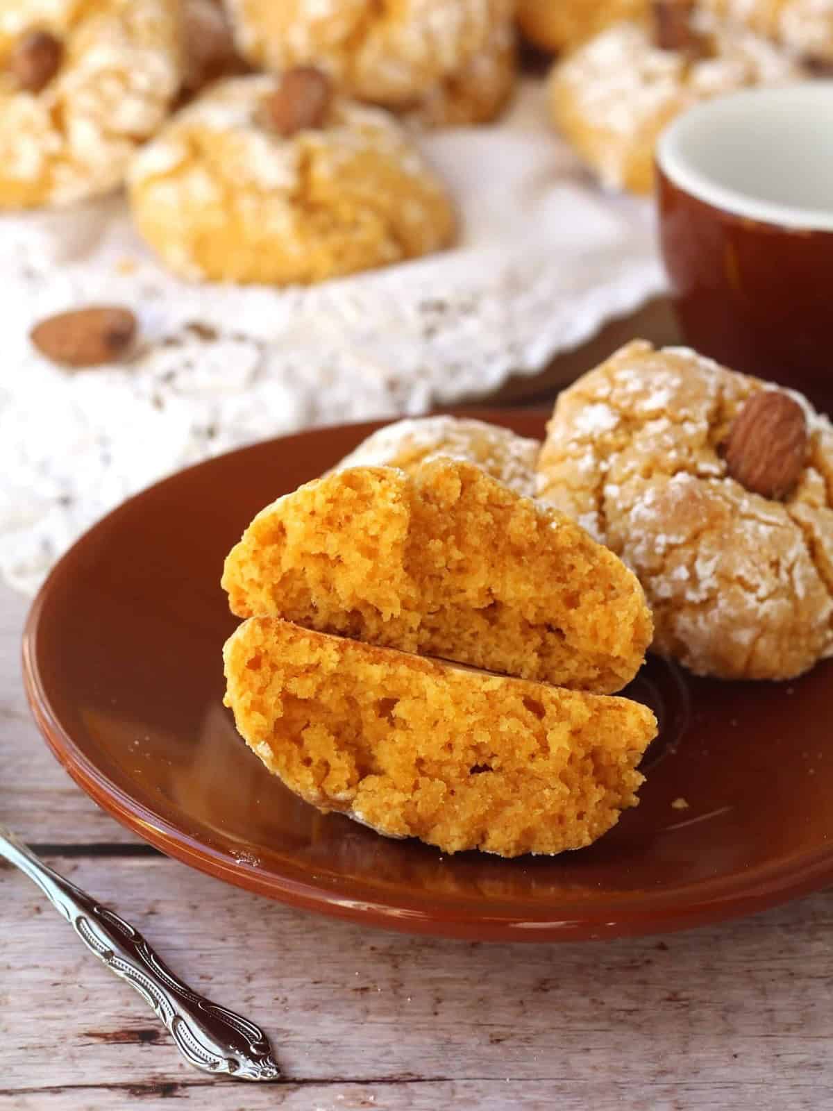 Soft pumpkin cookie with almond flour cut open on dish next to coffee cup.