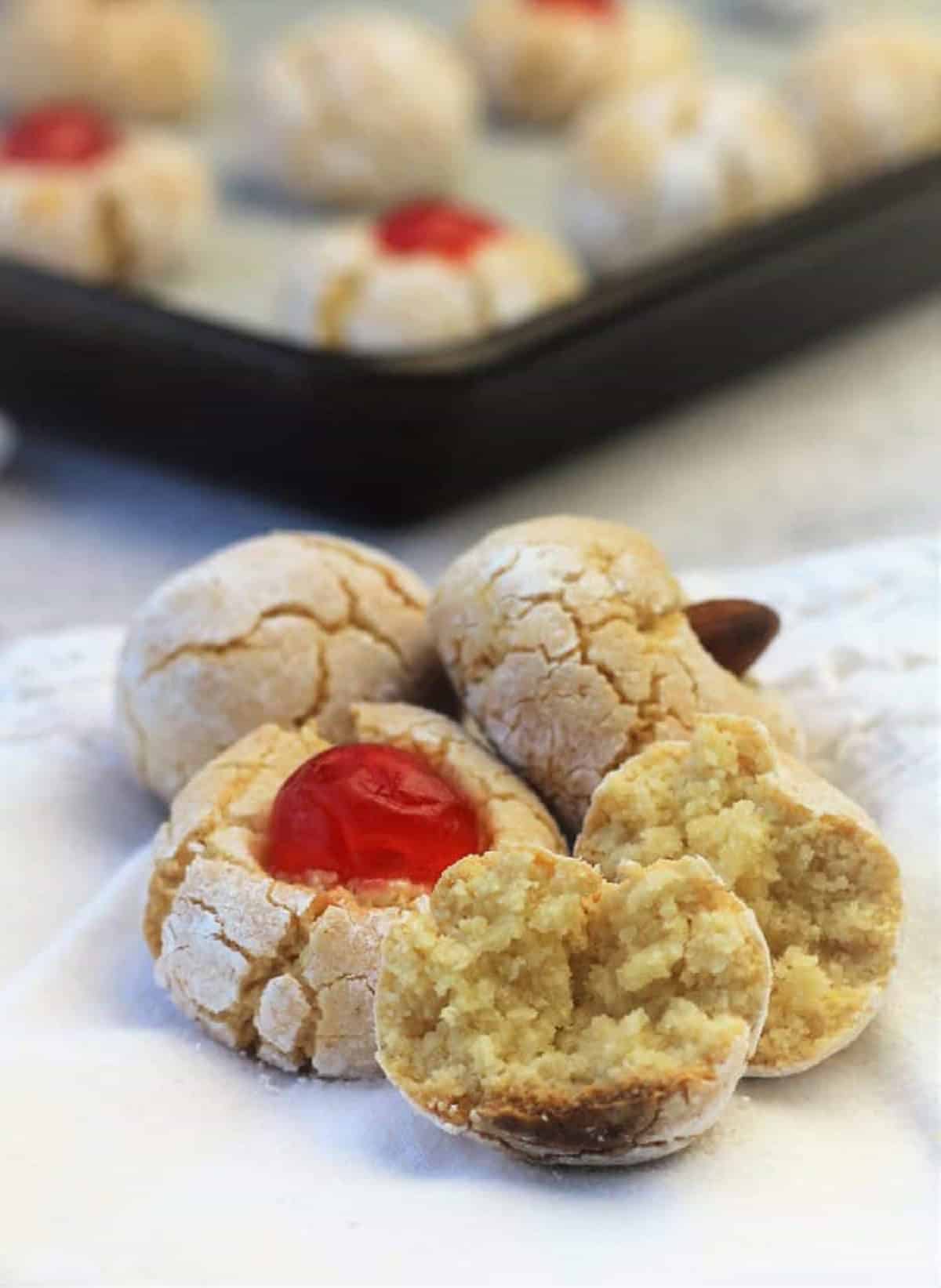 Italian almond cookie cut open next to other amaretti cookies.