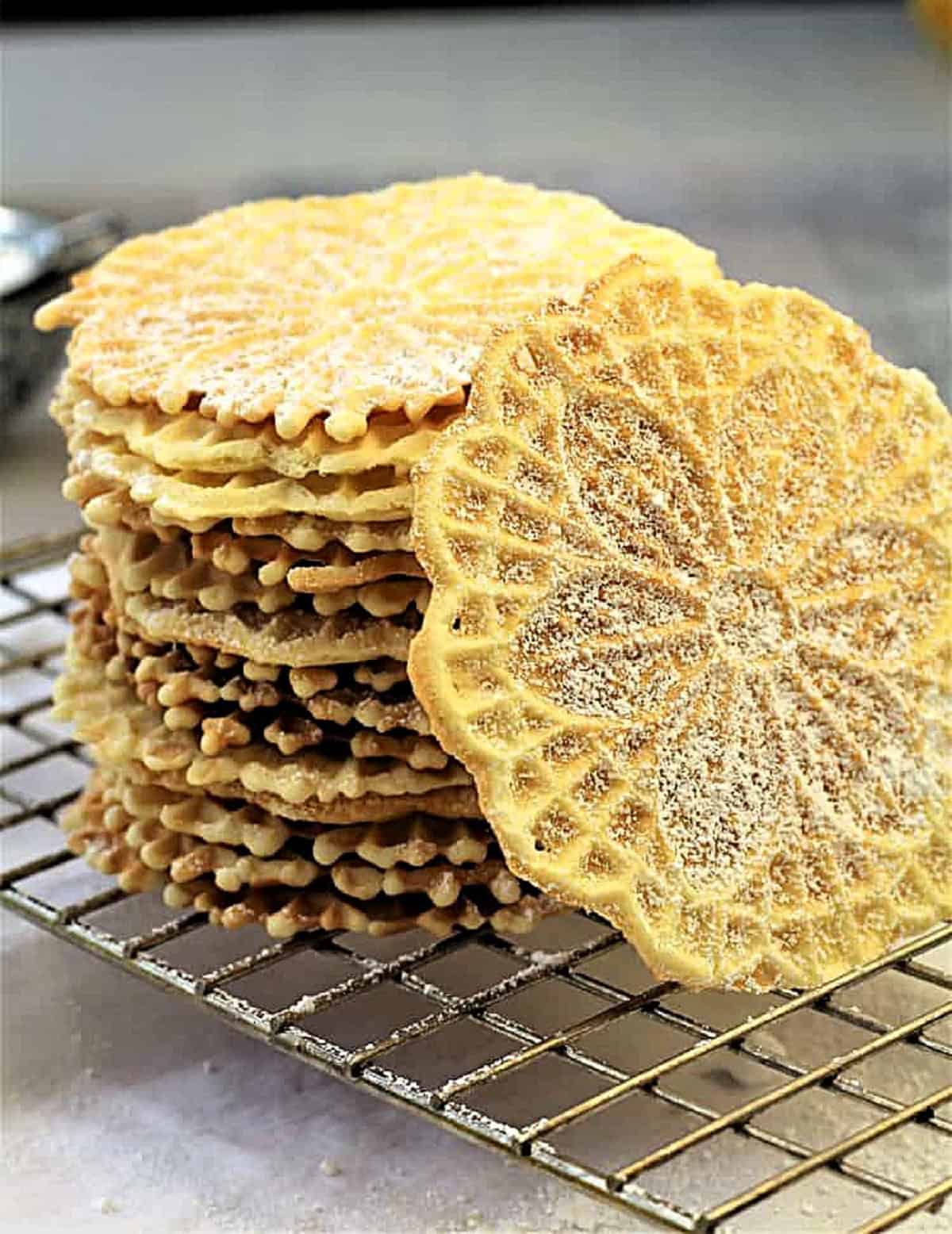 Pizzelle cookies stacked on wire rack.