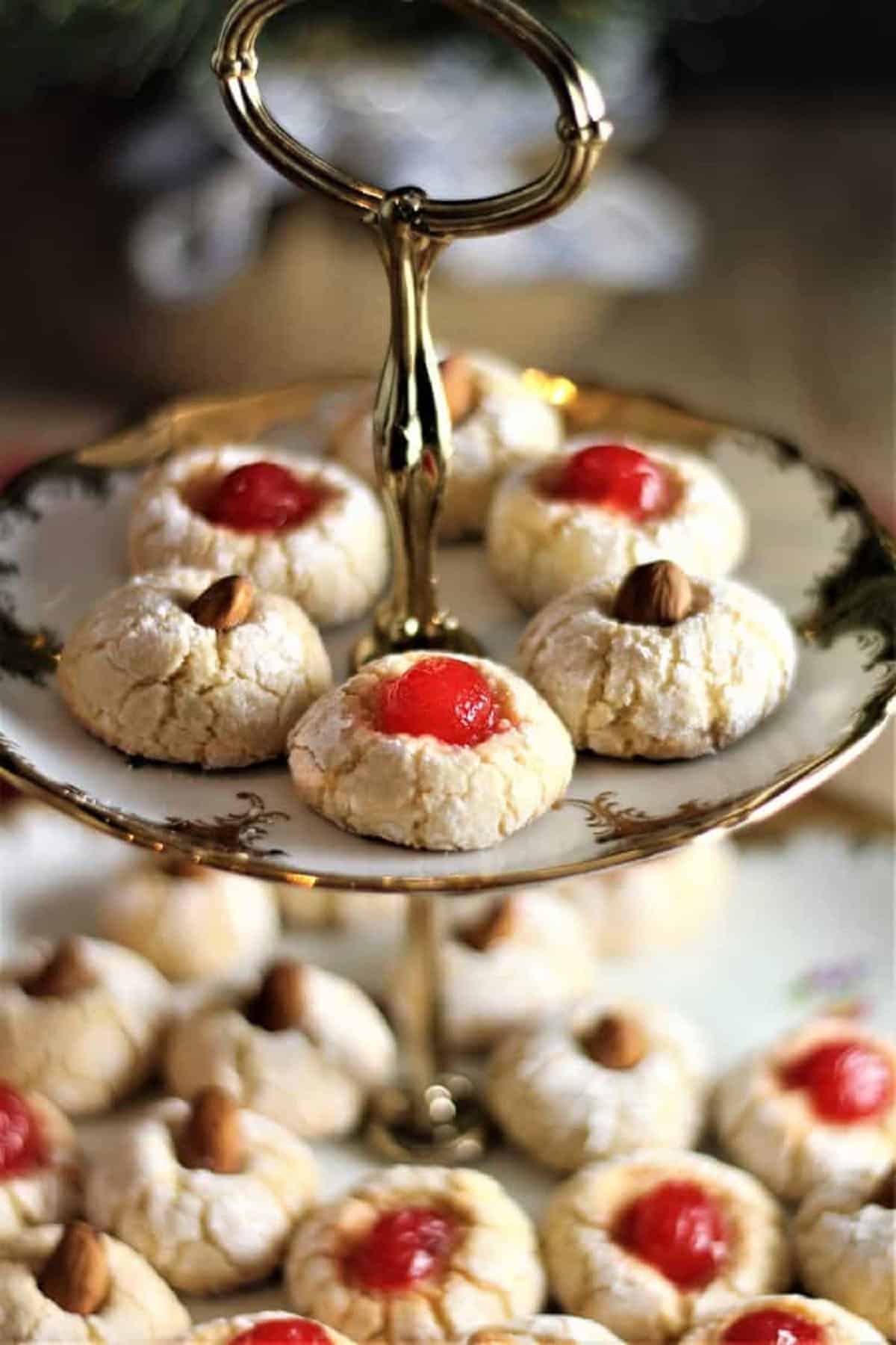 Soft amaretti cookies topped with cherries or almonds on cookie tray.
