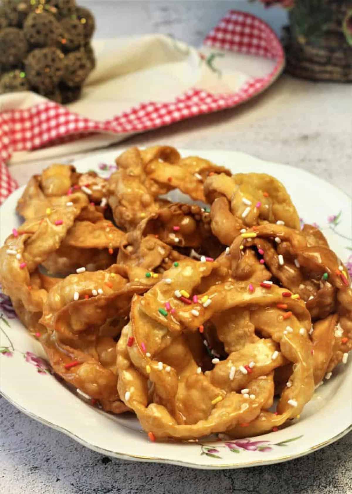 Braided pignolata drenched in honey on plate.